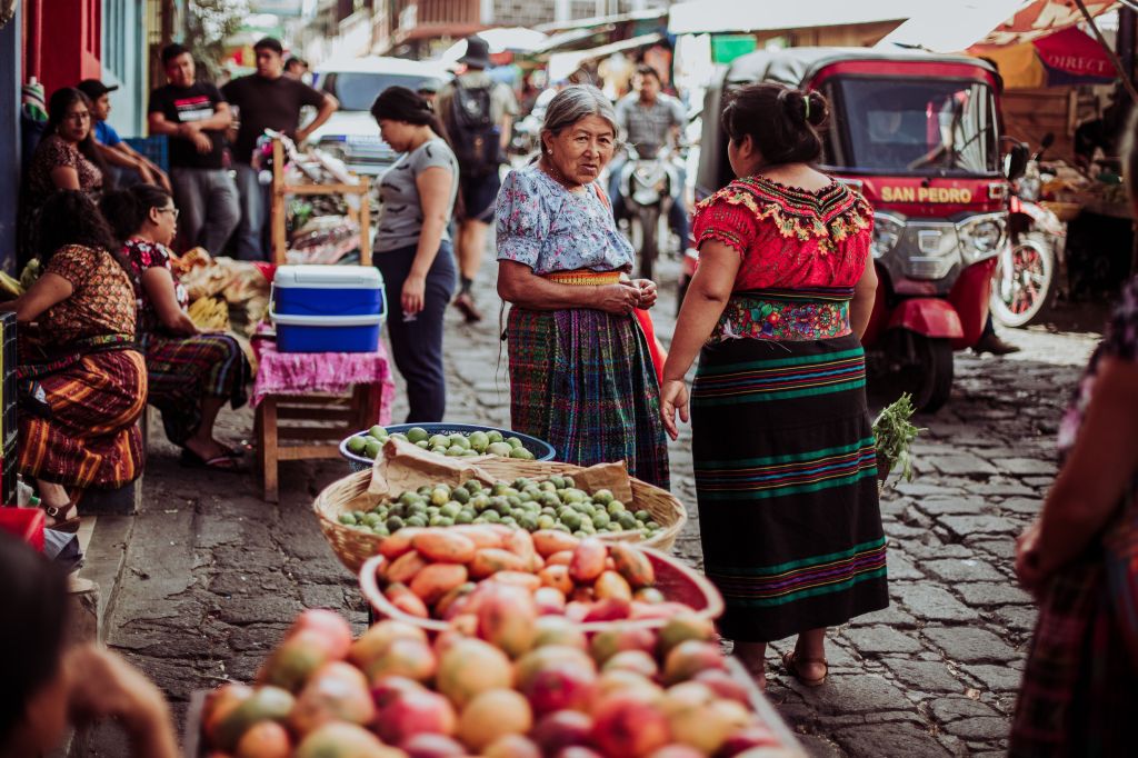 Community members gather and converse at a traditional market in Oaxaca, Mexico, surrounded by locally grown produce.